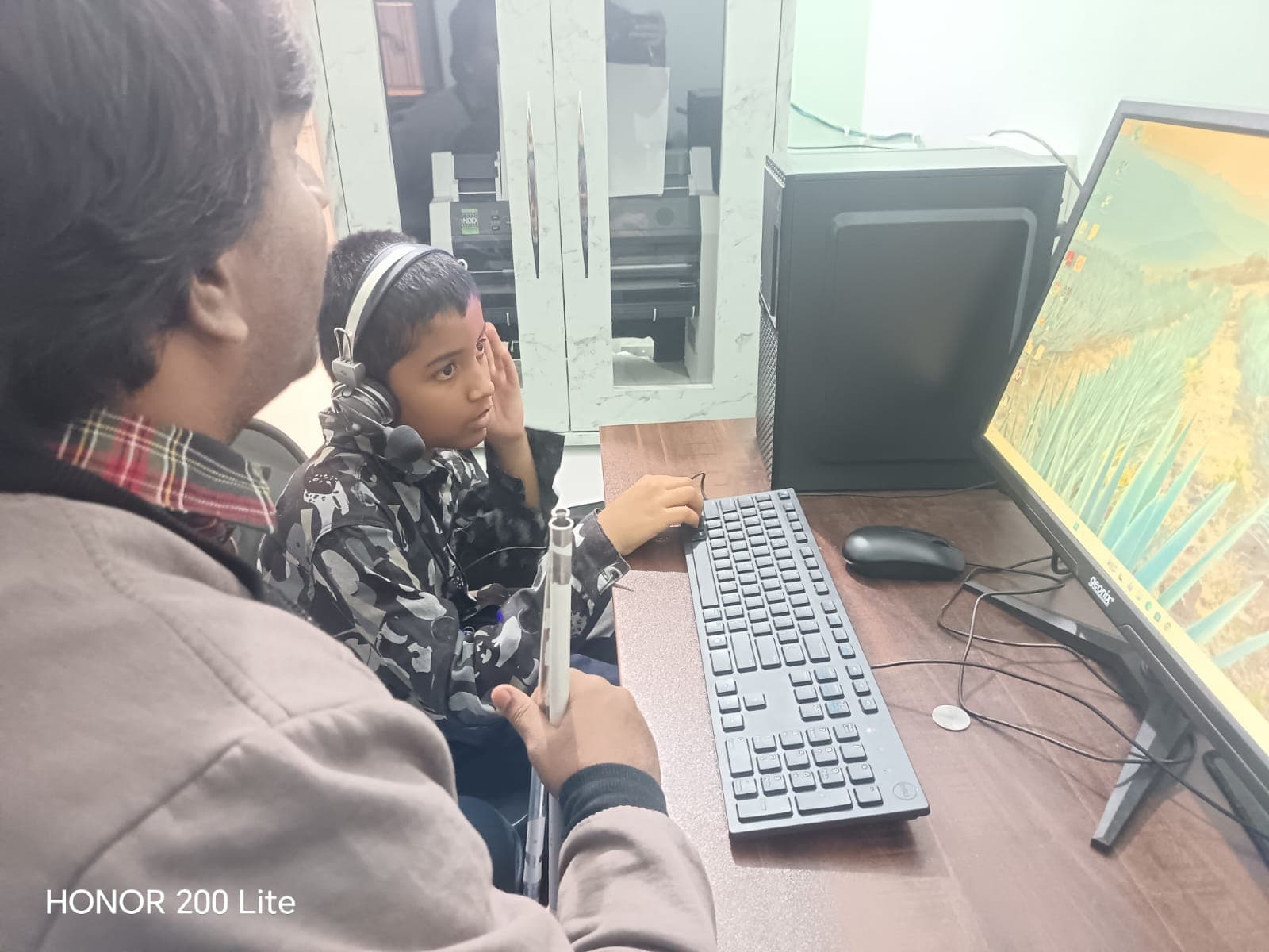 Specially abled person taking help of an abled young person to use computer